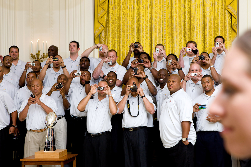Members of the Pittsburgh Steelers take photos as President Barack Obama walks into the room